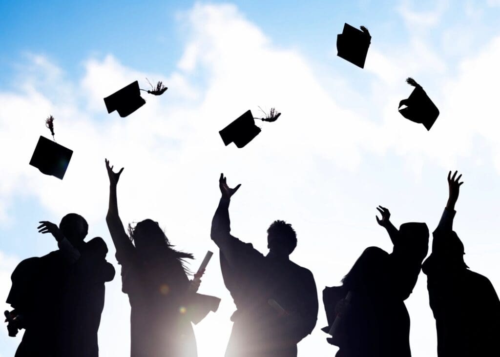 A group of people that are throwing their hats in the air